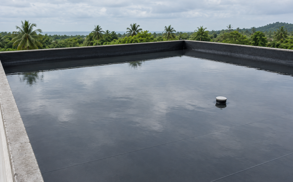Flat roof flooded with a shallow layer of water for a waterproofing flood test, dark membrane turned up at the edges