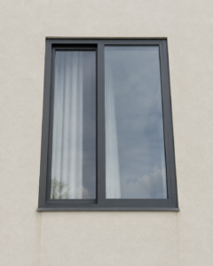 Window installed flush with the outer face of a rendered villa wall, with a flat sill